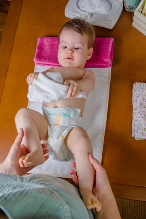 Adorable baby lying playing with a small white towel after the change of diaperの写真素材