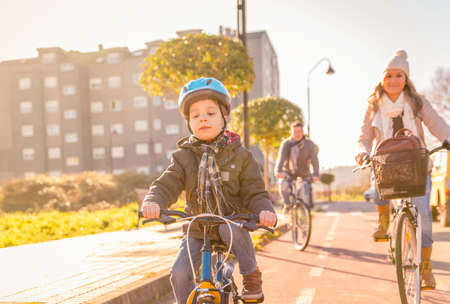Happy family with a child riding bicycles by the city on a sunny winter dayの写真素材