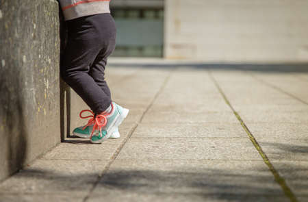 Closeup of little girl legs with sneakers and black leggins training outdoors
