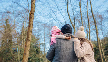 Back view of couple with her little daughter enjoying together of the forest landscape. Family leisure time concept.の写真素材