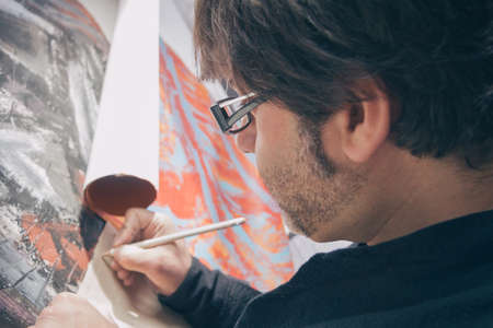Closeup of painter artist signing finished modern abstract oil canvas in his studioの写真素材