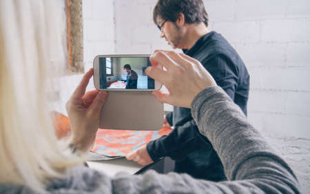 Closeup of woman hands taking a photo with a smartphone to painter artist working in a workshopの写真素材