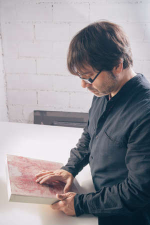 Portrait of painter artist reviewing a finished modern artwork in his studioの写真素材