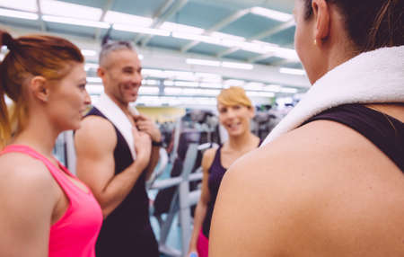 Group of women friends talking with personal trainer of a fitness center. Selective focus on a girl...