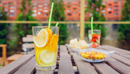 Infused fruit water cocktails and green vegetable smoothies over a wooden table outdoors. Healthy organic summer drinks concept.の写真素材