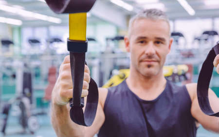 Closeup of fitness strap in the hand of man doing hard suspension training in a fitness center. Healthy and sporty lifestyle concept.の写真素材