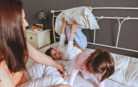 Portrait of happy family playing over the bed in a relaxed morning. Weekend family leisure time concept.の写真素材