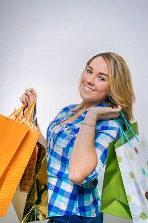 Portrait of happy girl teenager with blue plaid shirt holding shopping bags. Young consumer concept.の写真素材