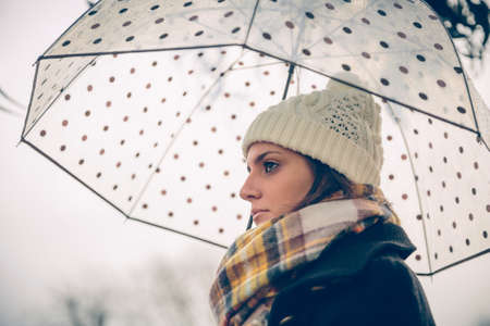 Closeup of young beautiful girl under a umbrella in an autumn rainy day