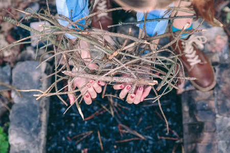 Top view of female hands holding firewood to start a bonfire over grill coals backgroundの写真素材