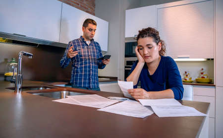 Desperate young couple with many debts reviewing their bills. Financial family problems concept.の写真素材