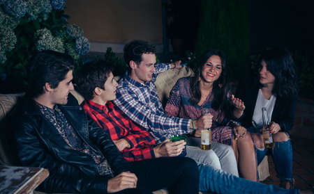 Happy young friends drinking and having fun in a outdoors party. Friendship and celebrations concept.の写真素材