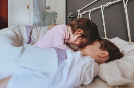 Portrait of happy little girl playing with boy over the bed in a relaxed morning. Weekend family leisure time concept.の写真素材