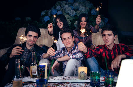 Group of happy young friends holding sparklers and having fun in a outdoors party. Friendship and celebrations concept.の写真素材