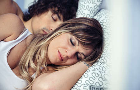 Closeup of young couple in love embracing relaxing together lying over a bed. Love and couple...