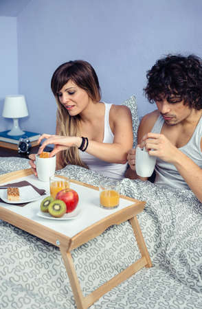 Young happy couple in love having breakfast in bed served over a tray at home. Couple home lifestyle concept.の写真素材