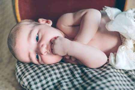 Portrait of adorable newborn baby resting lying over a plaid blanket on top of a vintage travel suitcaseの写真素材