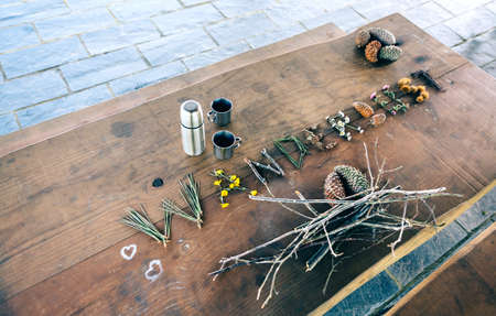 Wooden table with thermos, coffee cups and wanderlust word made with natural objectsの写真素材