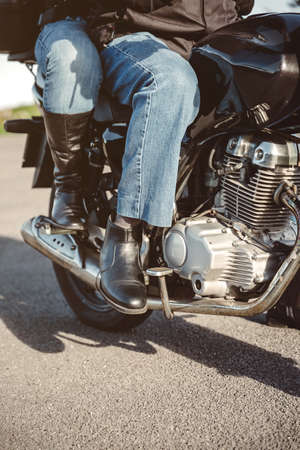 Senior couple legs with boots sitting over motorcycle ready to goの写真素材