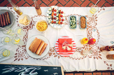 View from above of table with delicious food and drinks on tablecloth in a outdoors summer partyの写真素材