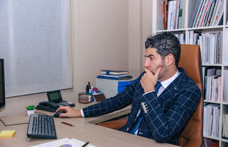 Serious businessman with jacket and tie looking computer in the office