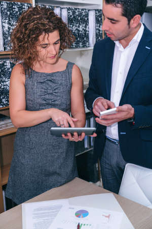 Close up of colleagues looking document in electronic tablet on a business meeting