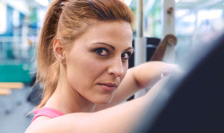 Beautiful sporty woman resting after lifting barbell on a muscular training in fitness center