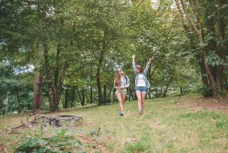 Young happy hiker woman raising arms and enjoying the nature with her female friend. Freedom and nature concept.の写真素材