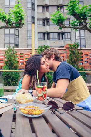 Young man whispering to beautiful woman sitting around of table with healthy drinks and snacks in a summer day outdoorsの写真素材