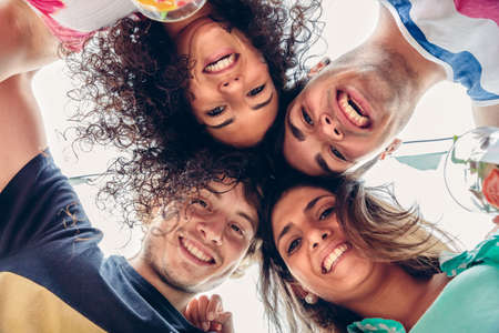 Close up of young happy people with their heads together having fun in a summer party. Young people lifestyle concept. View from below.の写真素材