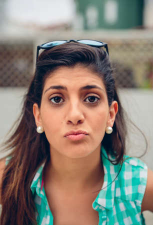 Close up of young woman with long hair blowing kiss at camera outdoors