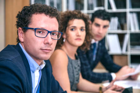 Executive chief sitting at negotiating table with teamの写真素材