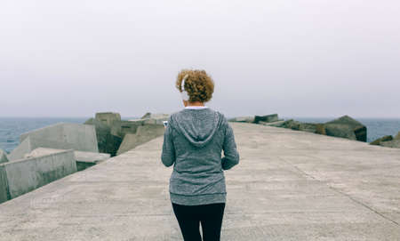 Back view of unrecognizable senior woman with headphones using smartphoneの写真素材