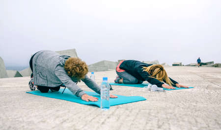 Unrecognizable young and senior woman stretching back outdoors by sea pierの写真素材
