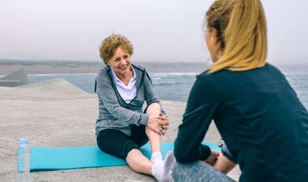 Senior sportswoman laughing with young woman by sea pierの写真素材