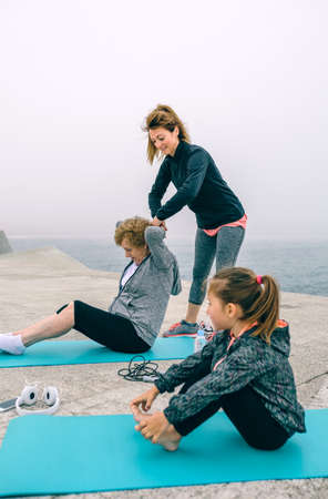 Senior and young woman exercising with little girl sittingの写真素材