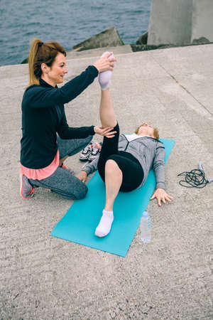 Young woman training senior woman by sea pierの写真素材