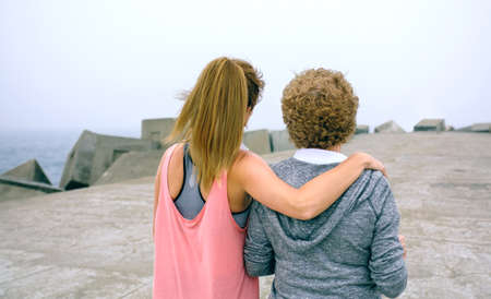 Back view of senior woman and young woman walking by sea pier