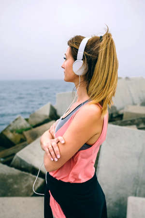 Side view of sportswoman with headphones watching the seaの写真素材