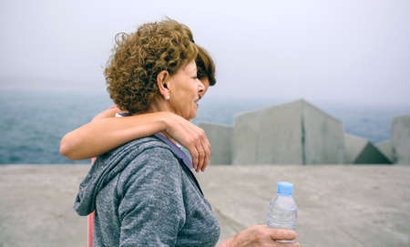 Senior woman and young woman walking outdoors by sea pierの写真素材