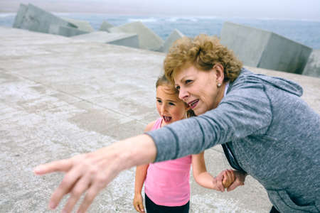 Senior sportswoman pointing while little girl is surprisedの写真素材