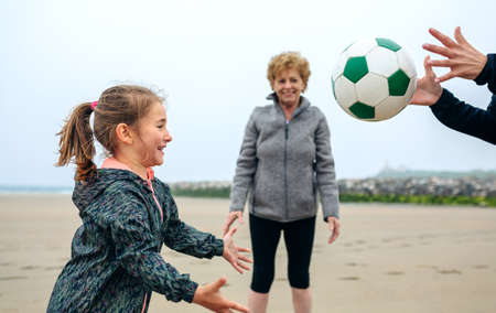 Three generations female playing on the beach in autumnの写真素材