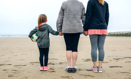 Back view of three generations female watching the sea in autumnの写真素材