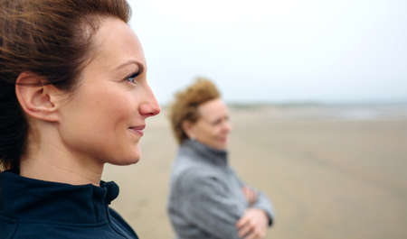 Two women looking at sea on the beach in autumn