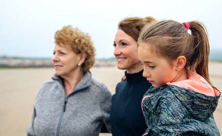 Closeup of three generations female looking at sea on the beach in autumnの写真素材