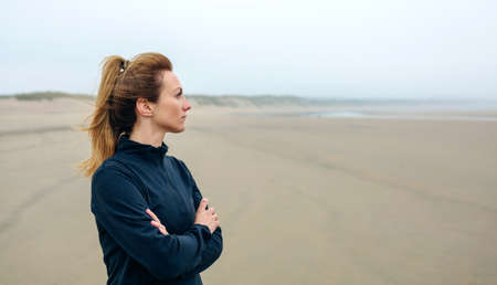 Woman looking at sea on the beach in autumnの写真素材