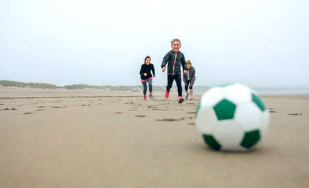 Soccer ball with three people running in the backgroundの写真素材