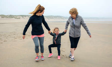 Three generations female running on the beach in autumnの写真素材
