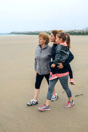 Three generations female looking at sea on the beach in autumnの写真素材