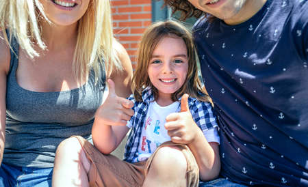 Closeup of child with parents sitting in front of their new homeの写真素材